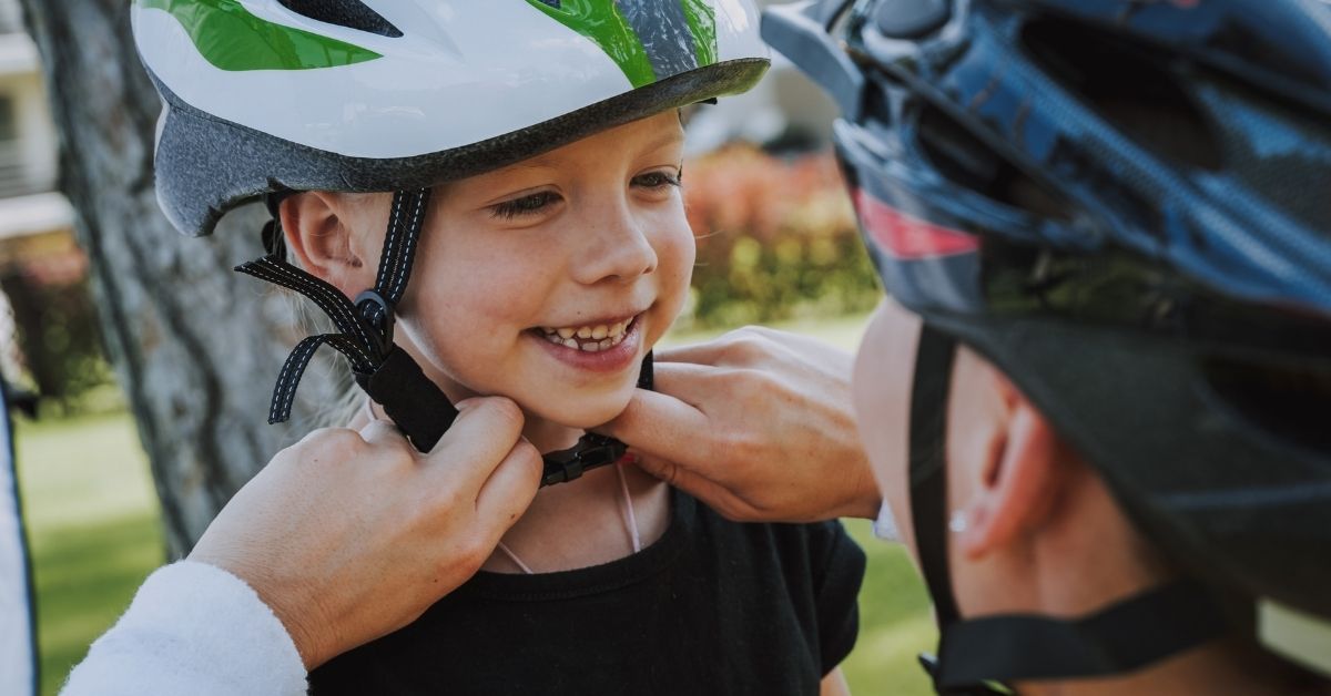 Mother puts cycling helmet of child