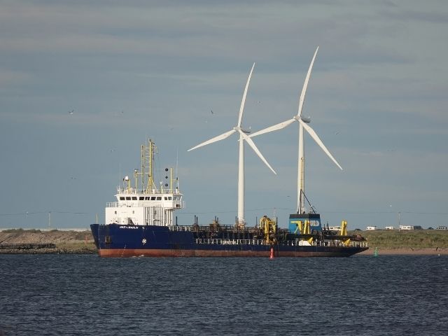 Freight ship with wind turbines in the background