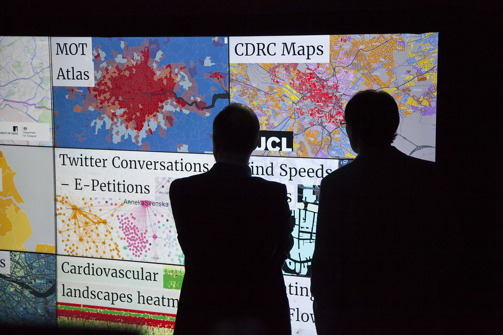 Two men look at digital maps on large screen