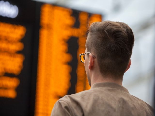 Man looks at train times on board at station