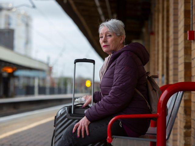 Woman in purple jacket sat at Warrington Bank Quay station