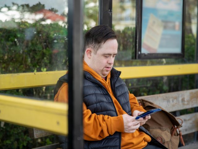 Man at bus stop with mobile phone